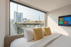 Bett in einem Zimmer mit einem großen Fenster in der Unterkunft Yello Rooms Hotel Victory Monument in Bangkok
