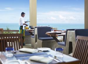 un hombre parado en una mesa en un restaurante con el océano en Jetwing Lighthouse en Galle