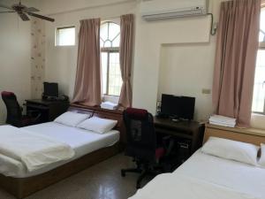 a room with two beds and a desk with a computer at Xiao Jinmen Homestay in Lieyu