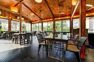 a dining room with tables and chairs and windows at Nitya Resort, Calangute in Calangute