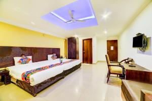 a bedroom with a bed and a desk and a television at Nitya Resort, Calangute in Calangute