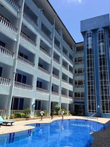 a large building with a swimming pool in front of it at Cowrie Luxury Beach Studio in Mombasa