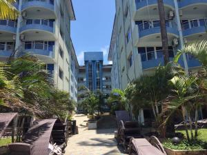 a resort with chairs and palm trees and buildings at Cowrie Luxury Beach Studio in Mombasa