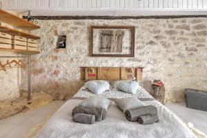 a bedroom with a large bed in a stone wall at Maison de vacances Le Mas des papillons in Fargues
