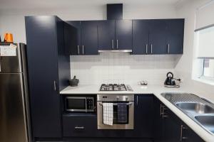 a kitchen with black cabinets and a stainless steel refrigerator at FortyTwo - Oceanside Retreat Busselton in Busselton