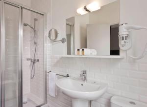 Un baño blanco con lavabo y ducha. en Hôtel des Ecrivains, en París