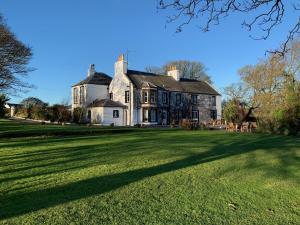 a large house with a large grass field in front of it at Torrs Warren Country House Hotel in Stoneykirk