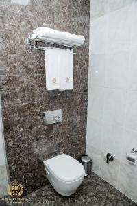 a bathroom with a toilet and towels on a wall at GM City Hotel in Baku