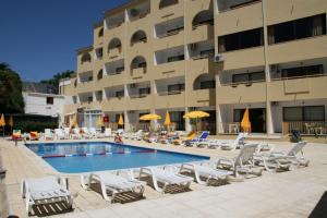 a hotel with a swimming pool and chairs and a building at Eirasol by Umbral in Albufeira