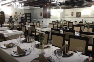 un comedor con mesas blancas y sillas con copas de vino en El Quijote, en El Toboso