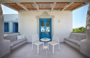 a porch with a table and chairs and a blue door at VOI Marsa Siclà Essentia in Sampieri