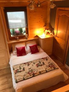 Schlafzimmer mit einem Bett mit roten Kissen und einem Fenster in der Unterkunft Gîte Bella Vita in Combloux