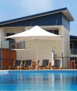 a white umbrella and chairs and a swimming pool at Broadwater Mariner Resort in Geraldton +8 photos
