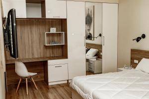 1 dormitorio con 1 cama blanca y 1 silla blanca en Loft apartment, en Leópolis