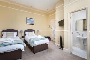 a hotel room with two beds and a sink at Crossways Guest House in Cheltenham