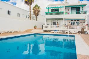 uma villa com piscina em frente a uma casa em Apartamentos Haría en Puerto del Carmen em Tías