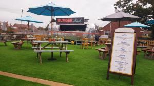 a picnic table with tables and umbrellas and a sign at Dunstan House in Burnham on Sea