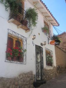 a white building with potted plants and a door at Hostal Madre Tierra in Cusco