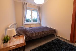 a small bedroom with a bed and a window at Victus Apartamenty, Apartament Avocado in Sopot