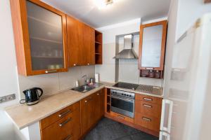 a small kitchen with wooden cabinets and a sink at Victus Apartamenty, Apartament Avocado in Sopot