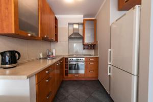 a kitchen with wooden cabinets and a white refrigerator at Victus Apartamenty, Apartament Avocado in Sopot
