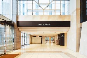un couloir dans un bâtiment avec un panneau indiquant la tour est dans l'établissement Shinagawa Prince Hotel East Tower, à Tokyo