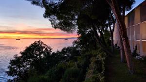 a sunset over the water in front of a building at Hotel Riviera & Maximilian's in Trieste