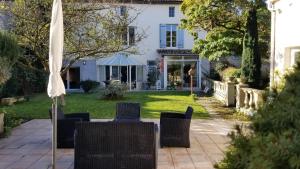 a patio with chairs and an umbrella in front of a house at La Maison Blanche in Blaye
