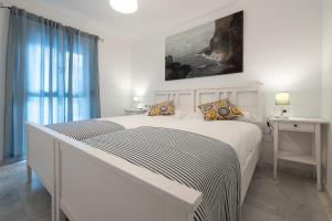 1 dormitorio blanco con 1 cama blanca grande con almohadas en Duplex La Corrala, en Cádiz