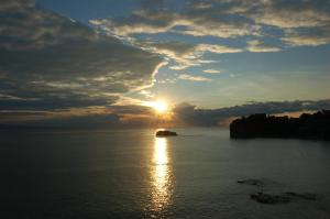 a sunset over a body of water with the sun setting at Hotel Lido Mediterranee in Taormina