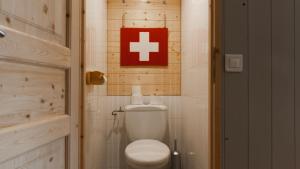 ein Badezimmer mit einem weißen WC und einem roten Kreuzschild in der Unterkunft La Roche Blanche in Val Thorens