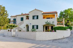 a large white house with a brick wall at Apartment Deni with central heating in Supetar
