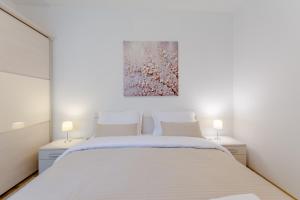 a bedroom with a white bed and two lamps at Apartment Deni with central heating in Supetar