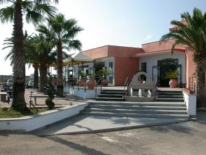 a building with palm trees and stairs in front of it at Hotel L' Anicrè in Marina di Varcaturo