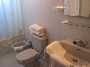 a bathroom with a toilet and a sink with towels at Apartamentos Turísticos Hawaii 4-5 in La Manga del Mar Menor