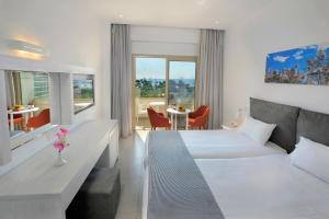 a hotel room with two beds and a table at Nissiana Hotel & Bungalows in Ayia Napa