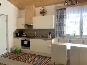 a kitchen with white cabinets and a large window at Haus Langegger Resi in Wagrain