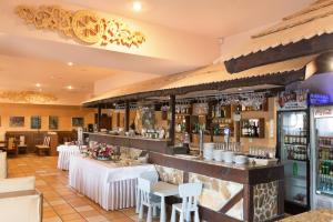 a restaurant with a bar with white tables and chairs at Zajazd Beskidy in Żywiec