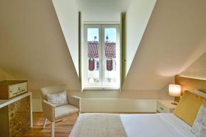 a bedroom with a bed and a chair and a window at My Story Hotel Ouro in Lisbon