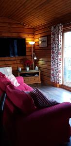 a living room with a red couch and a television at Glenmhor Log Cabin in Fort William