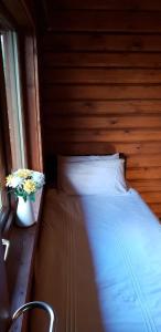 a bedroom with a bed and a vase with flowers at Glenmhor Log Cabin in Fort William