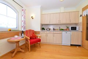 eine Küche mit einem roten Stuhl, einem Tisch und einem Fenster in der Unterkunft Landhaus Hubert's Hüs in Oberjoch