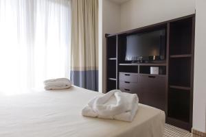 a bedroom with a bed with a television and towels at Hotel & Residence Villa Bartolomea in Villa Bartolomea