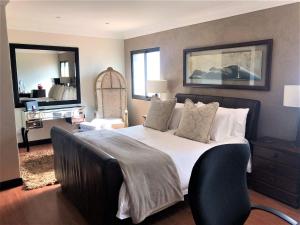1 dormitorio con 1 cama grande y espejo en Swanepoel Guesthouse & Suites, en Jeffreys Bay