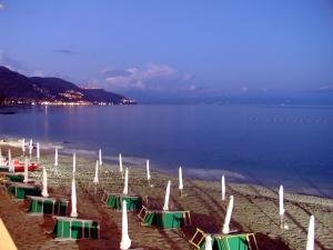 a beach with green and white umbrellas and the water at Hotel Lido Mediterranee in Taormina