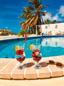 dos copas de bebidas en una mesa junto a una piscina en Karibu Aruba Boutique Hotel en Palm-Eagle Beach