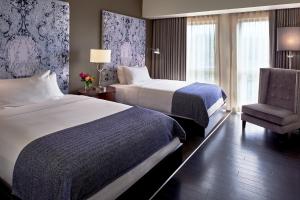 una habitación de hotel con 2 camas y una silla en The Fontaine en Kansas City