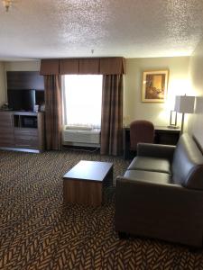a living room with a couch and a table in a hotel room at Baymont by Wyndham Oklahoma City Airport in Oklahoma City