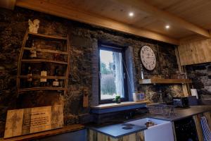 a kitchen with a window and a clock on the wall at Lusa Bothy in Lusa