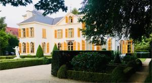 a large white house with a statue in front of it at Koetshuis Bosdam in Beveren